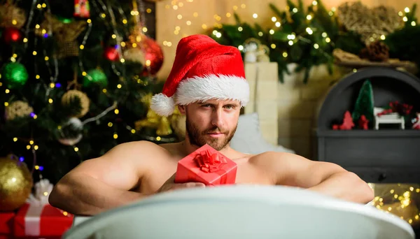Φροντίζω τον εαυτό μου. Χειμερινές διακοπές. Χριστουγεννιάτικη ιδέα. Ο άνθρωπος που βρίσκεται στην μπανιέρα χαλαρώστε με κουτί δώρου. Σπα και ευεξία. Ζεστό μπάνιο. Ζεστό μπάνιο οφέλη για την υγεία. Άγιος Βασίλης luxuriate σε ζεστό μπάνιο. Απόλαυσε. — Φωτογραφία Αρχείου