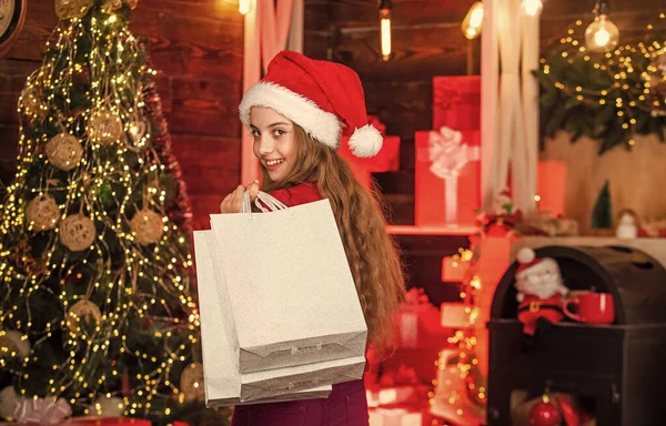 Shoppingnöje. Rentröja och tomteluva. shoppingpaket för familjen. En liten affärsman. barn leende med papperspåsar. julklappsshopping. Julen är här. nytt år vintersemester — Stockfoto