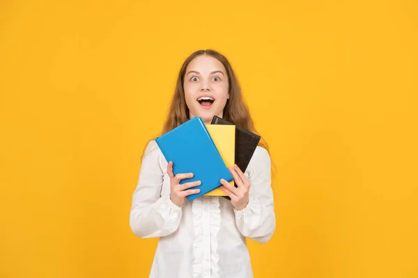 Verbaasd kind houden schoolboek over gele achtergrond, studie — Stockfoto