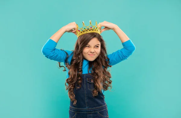Spiacevole teen girl con capelli ricci indossare corona su sfondo blu, egoismo — Foto Stock