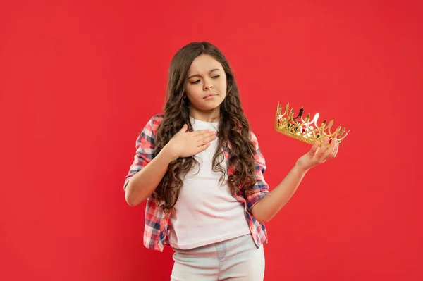 Arrogante niño con pelo rizado celebrar corona reina sobre fondo rojo, concurso — Foto de Stock