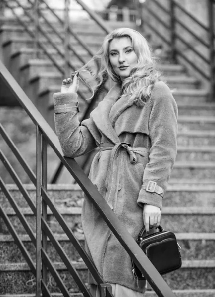 Herbstliches Outfit. Frau trägt stylisches Outfit und trägt Handtasche. Oberbekleidung aus modernem, warmem und stilvollem Öko-Pelz. Mädchen im warmen Mantel stehen urbanen Hintergrund. Erstellen Sie ein Herbst-Outfit, um sich wohl und hübsch zu fühlen — Stockfoto