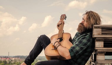 Akustik gitarist. Sakallı olgun hippi müzisyen. Gitar çalan vahşi beyaz adam. Country müziği. Sakallı adam şarkı söylüyor. Yakışıklı şarkıcı ve gitarist. Dinlenme zamanı.