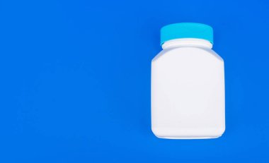 Mavi arkaplanda vitamin ve fotokopi alanı olan hap kavanozu beyaz rengi