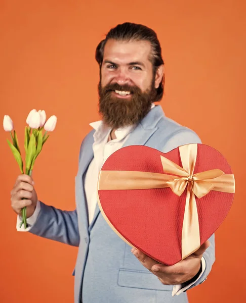 boxing day. formal party dress code. bearded hipster hold tulip flower bouquet. holiday present concept. brutal handsome man with love gift. valentines or womens day. masculinity and charisma