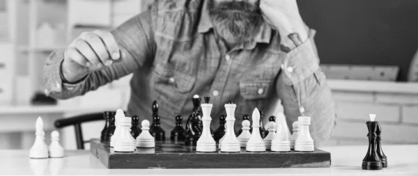 Figures on wooden chess board. Smart hipster man playing chess. Intellectual hobby. Thinking about next step. Chess is gymnasium of mind. Chess lesson. Strategy concept. School teacher. Board game