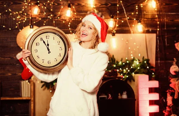Timing. Gelukkig nieuwjaar. Kerstvoorbereiding. meisje met de rode kerstman hoed. Middernacht. Vrolijke vrouw, tijd om het te vieren. wintervakantie. Het is tijd voor kerst. Kerststemming. Vrouw met klok — Stockfoto