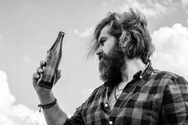 Un type ordinaire qui boit de la bière. hipster brutal avec les cheveux longs et la moustache se détendre en plein air. soins de santé masculins. concept d'hydratation. homme barbu en chemise à carreaux boire de l'eau de la bouteille — Photo