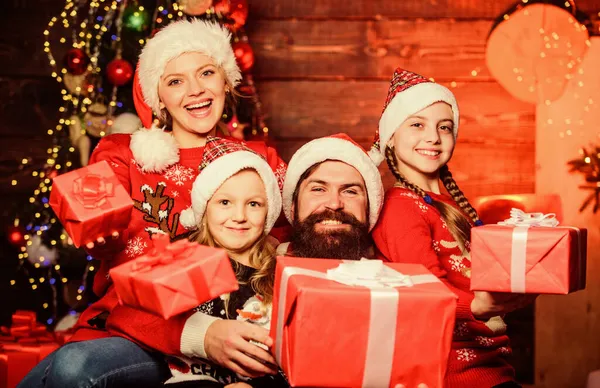 Ouders en kinderen openen kerstcadeaus. Vader Kerstman en moeder kleine dochters kerstboom achtergrond. Kersttraditie. Vrolijk familieconcept. Kerstvreugde. Fijne feestdagen — Stockfoto