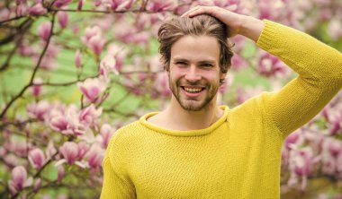 Hippi çiçek aromasının tadını çıkarır. İlkbahar konsepti. Tıraşsız bir adam manolya çiçeği koklar. Erkek çiçekli arka plan çözüldü. Bahar güzeli. Bahar sezonu. Botanik ve doğa. Mutlu bahar konsepti