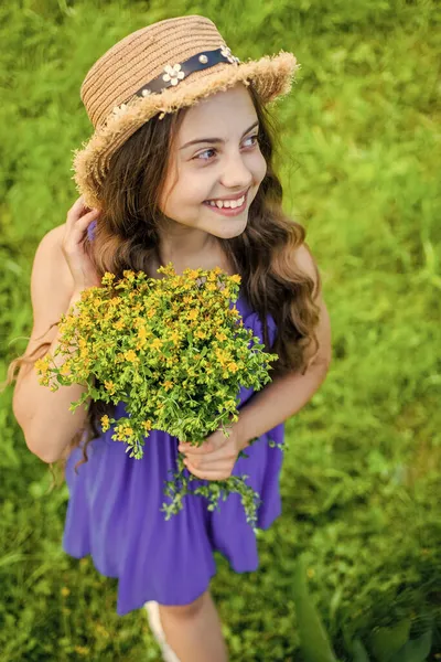 Söt leende flicka bär halm hatt samla gula blommor i fält — Stockfoto