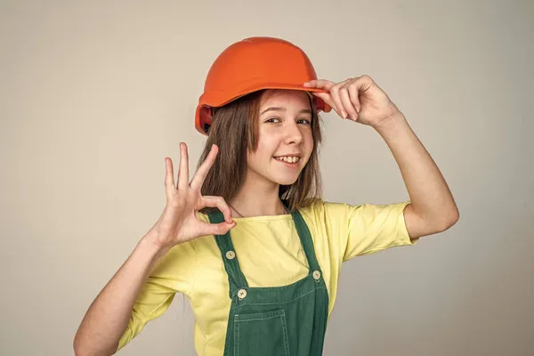 Инженер подросток строитель. Международный день трудящихся. Озил показывает хороший жест. Девушка в шлеме играет строителя. строительство и ремонт. Ребенок строит. ОК жест — стоковое фото