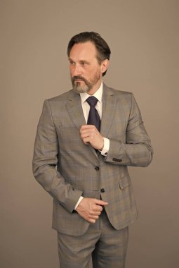 Kazanan bir tavrın var. Resmi tarzda olgun bir adam. İş adamının modaya uygun görünüşü. Ofis tarzı. İş kıyafeti. Moda dolabı. Erkek giyim mağazası. Özel bir kıyafet al. Sakallı adam gri arka plan