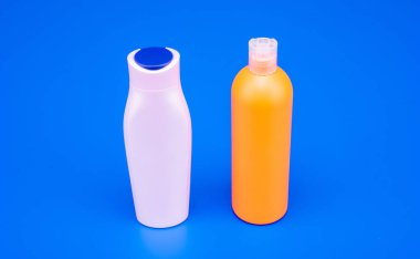 HDPE mavi arka plan. Yenilenebilir şampuan ve saç kremi şişeleri. Plastik kozmetik paketleme şişeleri