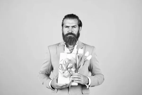 Être ma valentine. concept actuel de vacances. homme beau brutal avec boîte cadeau. Saint Valentin ou jour des femmes. masculinité et charisme. code vestimentaire officiel. barbu hipster tenir bouquet de fleurs de tulipe — Photo