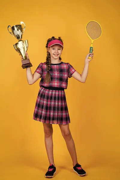 Tini gyerek fitness sapkában kezében tenisz vagy tollaslabda ütő és bajnokság kupa, sport bajnok — Stock Fotó
