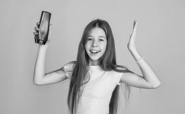 Uzun düz saçlı neşeli kız saç kremi şampuan ya da jöle şişesi, duş.