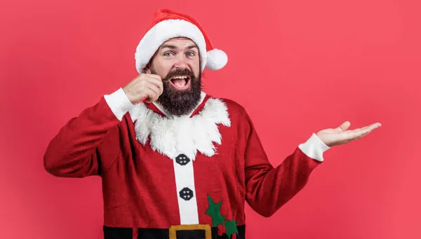 Surprised male hipster with beard and moustache wearing santa costume for xmas party celebration presenting product, copy space, winter shopping — Stock Photo, Image