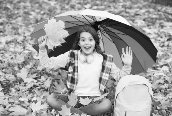 Vítěz dne. Podzimní dítě pod barevným deštníkem. cítit inspiraci. Šťastné dětství. Zpátky do školy. dívka s batohem v parku. užijte si pád v lese. dítě sbírat žluté padlé javorové listy — Stock fotografie