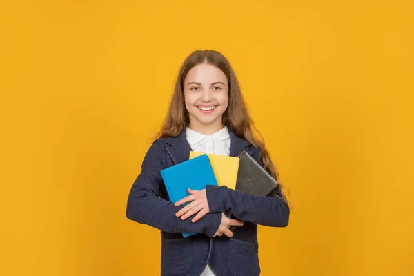 행복 한 여학생 이 노란 배경에 대한 학교 숙제 책을 가지고 있습니다. — 스톡 사진