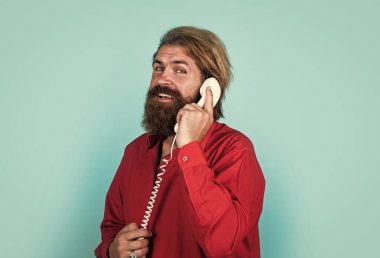 Konuşma. Modern görünümlü sakallı hippi telefonda konuşuyor. İletişim konsepti. Bıyıklı vahşi yakışıklı adam klasik telefon kullanıyor. olgun yönetici ya da yardımcısı