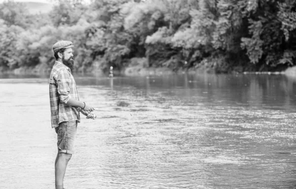 钓鱼的乐趣正在吸引人.渔民与捕鱼设备。钓到鱼了残忍的男人穿着橡胶靴站在河里.费雪周末活动在野外休闲。钓鱼男性爱好 — 图库照片