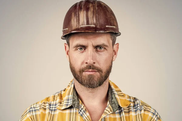 man architect with serious look. guy wear worker uniform. handsome builder in helmet. mature man wear checkered shirt. professional constructor or mechanic. builder engineer