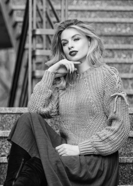 Giyilebilir trendler. Sonbahar formülü. Sonbahar için Süveter ve Etek Kombo stili. Harika saç stili olan kadın merdivenlerde dışarıda oturuyor. Sonbahar moda trendi. Kız eteğinin üzerine büyük katman örülmüş.