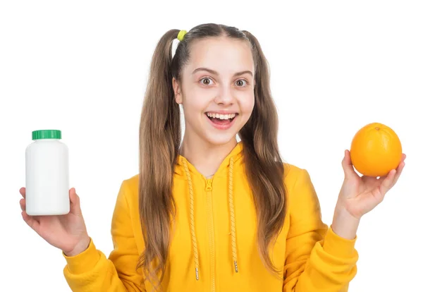 Chica elegir entre fruta naranja y vitamina píldora en frasco aislado en blanco, multivitaminas. — Foto de Stock