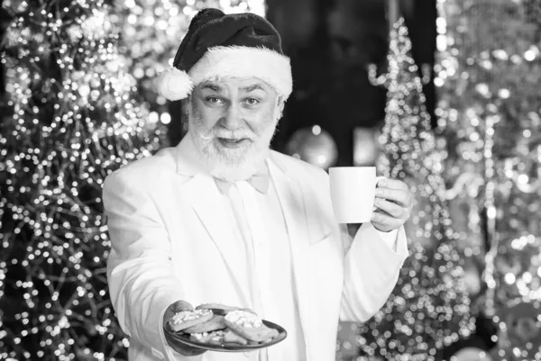 クリスマスツリーの近くにサンタクロース。メリークリスマス。髭を生やしたサンタクロース。サンタクロースはリラックス。冬休み。老人ホームでおじいちゃん。伝統の概念。コーヒー休憩。スイーツとお菓子 — ストック写真