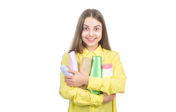 Счастливый ребенок представляет шампунь или бутылку кондиционера для волос, изолированную на белом, трихолог — стоковое фото
