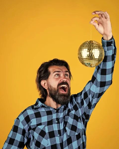 Περιεχόμενο άνθρωπος σε καρό πουκάμισο με χαρούμενο πρόσωπο κρατώντας λαμπερό ντίσκο μπάλα ποζάρουν σε κίτρινο, διασκέδαση κόμμα — Φωτογραφία Αρχείου