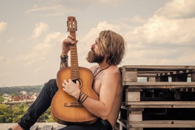 Yakışıklı sakallı, şık saçlı, akustik gitar çalan, telli çalgı çalan adam.