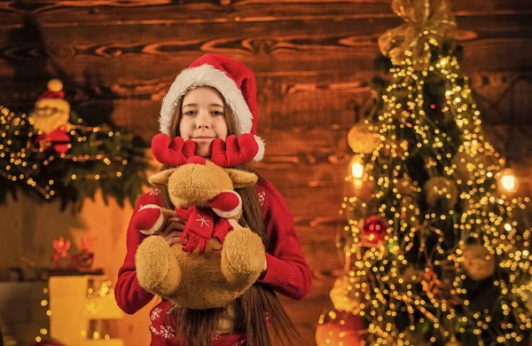 Час для чудес. Все, що я хочу на Різдво. Милі олені. Щастя і радість. Дитяча щаслива дівчина знаходить подарунки на ялинку. Веселого Різдва. Щаслива концепція дитинства. Дитячий капелюх Санта. Санта приніс подарунки — стокове фото