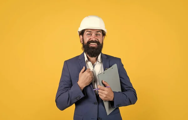 Férfi öltöny és építési sisak keres az oldalon, és gazdaság mappa sárga háttér, építészet — Stock Fotó