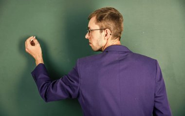 Okula dönüyorum. Üniversite öğretmeni tahtaya yazı yazar. Kolejde öğrenci eğitimi. Modern eğitim konsepti. Genç ama yetenekli bir iş adamı. Tipik bir ofis çalışanı. Adam gözlük ve ceket giyiyor.