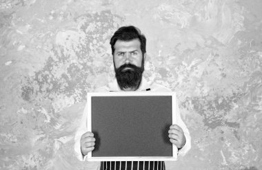 Vahşi sakallı adam şef boş panoda fotokopi alanı reklamı ve reklamı için restoran menüsü sunuyor.