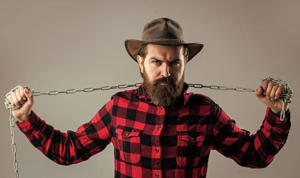 Não desistas. acorrentado em correntes. O homem barbudo tem um aspecto agressivo. expressar a sua força. poder masculino e masculinidade. cadeia de quebra hipster maduro. Um grilhão. brutal homem no cowboy chapéu com corrente — Fotografia de Stock