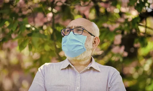Ciesz się pięknem. Człowiek w Sakura w masce ochronnej. zapach kwitnących kwiatów na kwarantannie koronawirusowej. zachować ostrożność podczas pandemii. zdrowe życie. nosić maskę w kwitnącym różowym parku sakura — Zdjęcie stockowe