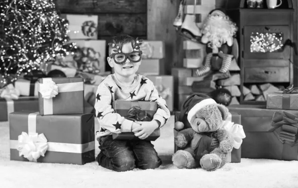 Humor de Navidad. niño mantenga bola decorativa. regalo de juguete de oso para en Navidad. Feliz navidad. Feliz año nuevo. Gafas de fiesta infantiles felices. Santa son celebrar las vacaciones de invierno. pequeño chico excitado con presente —  Fotos de Stock