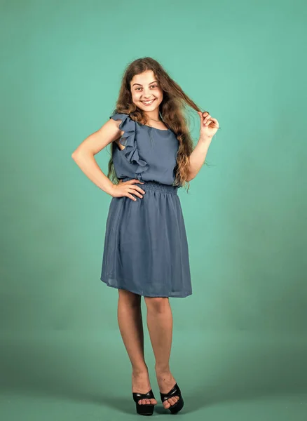 Bela menina adolescente com cabelo encaracolado longo. Estilo de moda infantil. beleza natural feminina. infância feliz. bonito criança no fundo verde. salão de cabeleireiro. olhar na moda elegante — Fotografia de Stock