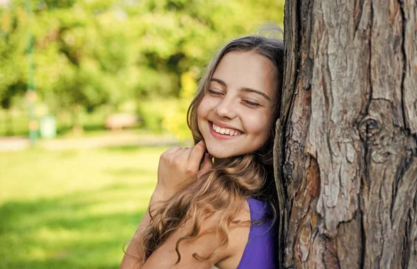 Bebê feliz menina sorriso com beleza olhar olhos fechados no tronco da árvore na paisagem ensolarada verão, felicidade — Fotografia de Stock
