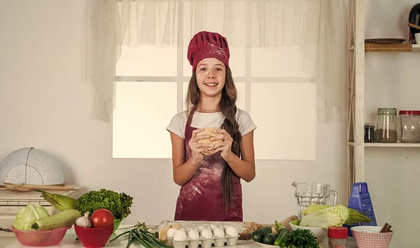 부엌에서 굽는 작은 소녀. 아이 요리사가 반죽을 만들고 있습니다. 아이들은 집에서 건강에 좋은 음식을 준비하고 요리용 유니폼을 입습니다. 집안일과 집안일을 돕는 일. 아동 발달. 전문 요리사 — 스톡 사진