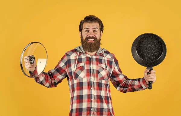 Hipster masculino con pelo peinado de moda y barba cocina con sartén, cocina —  Fotos de Stock