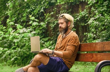 Yetişkin bir adam dizüstü bilgisayarla parkta oturuyor ve e-postaları kontrol ediyor. Bilgisayar üzerinde çalışan serbest çalışan bir adam. İş adamı parkta defter kullanıyor. Ofisten kaçtı. Başarılı bir girişimci. Okul eğitimi