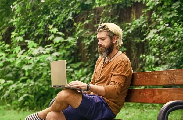 Yetişkin bir adam dizüstü bilgisayarla parkta oturuyor ve e-postaları kontrol ediyor. Bilgisayar üzerinde çalışan serbest çalışan bir adam. İş adamı parkta defter kullanıyor. Ofisten kaçtı. Başarılı bir girişimci. Okul eğitimi — Stok fotoğraf