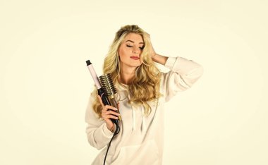 Bunu gerçekleştireceğiz. Güzel yüz. Kuaför salonu konsepti. Sağlıklı uzun sarı saç. Saç maşası kullanan uzun saçlı bir kadın. Güzellik ve moda. Saç stili dalgalı bukleler. Mükemmel makyaj ve kıvrımlar.