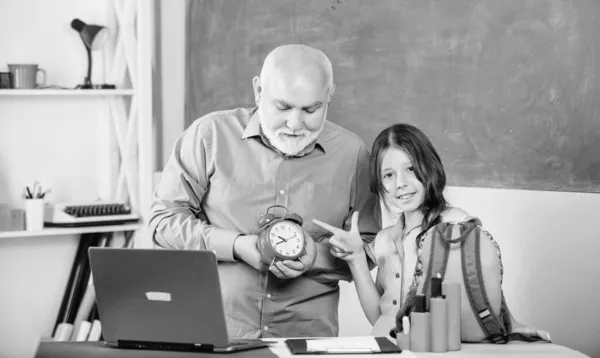 Tarde a la escuela. blogueo educativo. De vuelta a la escuela. niña pequeña con hombre tutor estudio en la computadora. alarma de rotura. Buenos días. tiempo para estudiar. lección de la escuela en línea. maestro maduro ayuda alumno con reloj —  Fotos de Stock