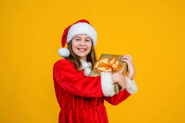 圣诞节快乐的小女孩戴着红色的圣诞老人帽，头戴服装，拿着礼品盒，购物 — 图库照片