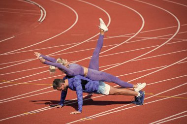 Fitness partnerleri yükseliyor. Atletik erkek ve seksi kadın yan yana. Stadyum arenasında erkek ve kadın koç. Sağlıklı bir yaşam tarzı. Güç ve güç. Spor çifti eğitimi.